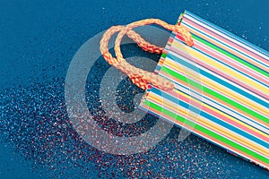 Striped gift bag on abstract red, white and blue glitter sparkle background. Holiday concept