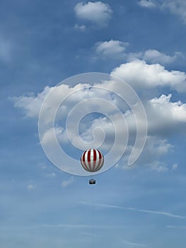 Striped hot air balloon soars in the blue sky against the background of white clouds