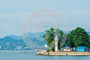 Striped lighthouse on the city shore, photograph