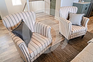 Striped living room armchairs of home with wooden floor and carpet