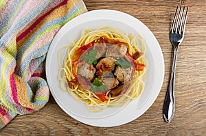 Striped napkin, plate with fried pork meat with lecho and spaghetti, fork on table. Top view