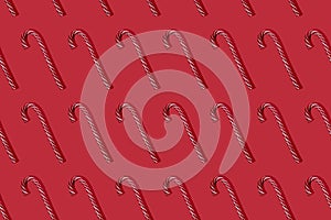 Striped red and white candy canes on red background. Trendy seamless pattern. Flat lay witn Cristmas lollipop hard light