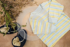 Striped shirt and booties for newborn boy. Baby`s clothes and bouquet of flowers. Expecting a baby. Flatlay design.