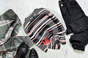 Striped sweater, black jeans and scarf. Red maple leaf. Fashionable concept