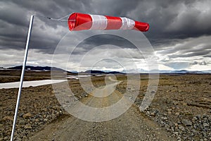 Striped Windbag and Mountain Gravel Road with dark clouds, Kaldidalur, Iceland. Concept for creative business ideas.