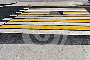 Striped yellow and white pedestrian zebra crossing on gray asphalt, abstract background. Crosswalk on the road for people`s safet