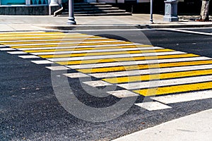 Striped yellow and white pedestrian zebra crossing on gray asphalt, abstract background. Crosswalk on the road for people`s safet