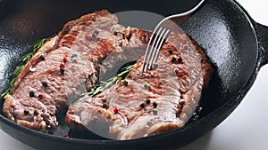 Striploin beef steak cooked in iron skillet closeup view.
