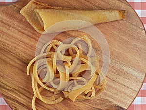 Strips of salted raw pork rind strips set on a wooden board