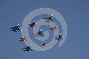 The `Strizhi` and `Russian Knights` aerobatic teams are flying in the sky over Red Square during the parade. photo