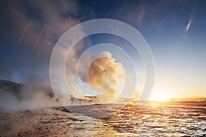 Strokkur geyser eruption in Iceland. Fantastic colors shine through the steam. Beautiful pink clouds in a blue sky