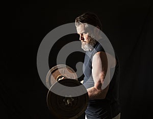 Strong, active, middle aged man with gray beard lifting heavy weights in studio setting