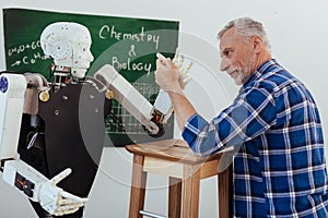 Strong aged man looking at the robot