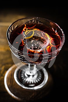 Strong alcoholic drink of brandy whiskey in a glass with ice cubes on a dark wooden background. Top view