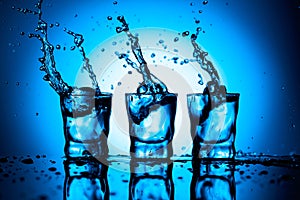 Strong alcoholic drink in dammed glasses with splashes on a blue background