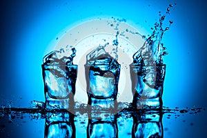 Strong alcoholic drink in dammed glasses with splashes on a blue background