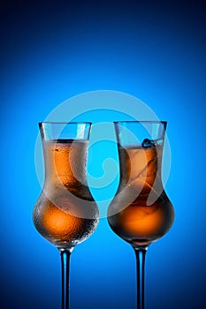 Strong alcoholic drinks in dammed glasses with ice on a blue background