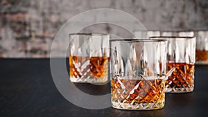 Strong alcoholic drinks, glasses and glasses, in the presence of whiskey, brandy. on a dark background of an old wooden table