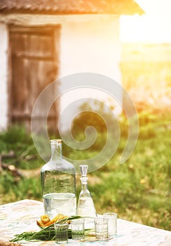 Strong alcoholic homemade drink moonshine in glass vintage containers and pickled cucumbers. Traditional rural still life of Ukrai