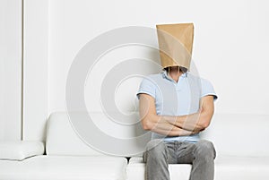 Strong anonymous man sitting on sofa with arms crossed.