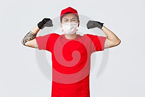 Strong asian delivery guy in red cap, t-shirt show-off his strength, flex biceps bragging muscles as carry large boxes
