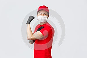 Strong asian guy show-off his strength, carry large parcels at work. Delivery man in uniform flex biceps and grimacing