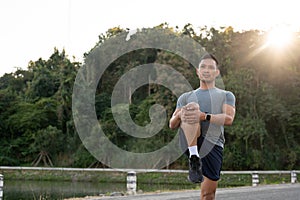 Strong, athlete Asian man in sportswear is stretching his legs and body, warming up before exercise