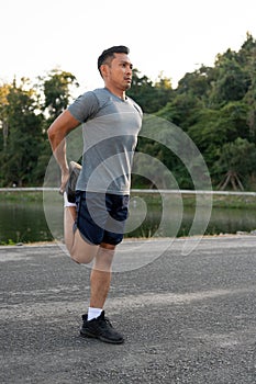 Strong, athlete Asian man in sportswear is stretching his legs and body, warming up before exercise