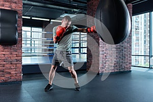 Strong athlete boxing hard wearing red gloves