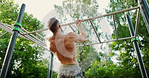 Strong athlete doing pull-up on horizontal bar.Young athletic man showing back at sports ground