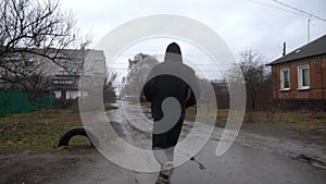 Strong athlete running along country road in the rain. Young sportsman jogging along rural trail at cloudy day. Athletic