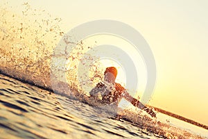 Strong athlete splashing in the water at sunset