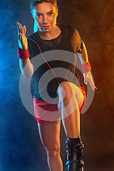 A Strong athletic, female runner on the black bacground wearing a tight, fitness outfit. Sports girl in shoes for kangoo