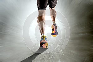 Strong athletic legs with ripped calf muscle of sport man running on motion grunge background photo