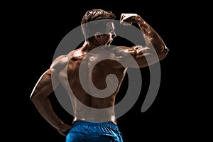 Strong Athletic Man Fitness Model posing back muscles, triceps over black background
