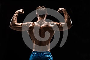 Strong Athletic Man Fitness Model posing back muscles, triceps over black background