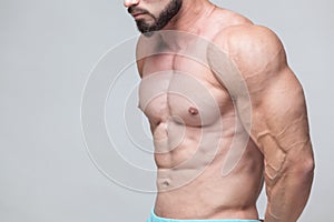 Strong Athletic Man Fitness Model Torso showing six pack abs. on grey background with copyspace