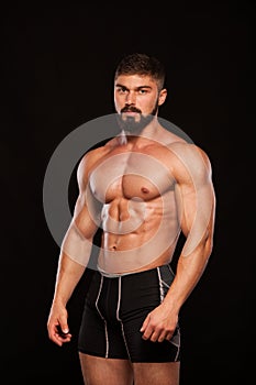 Strong Athletic Man Fitness Model Torso showing six pack abs. isolated on black background with copyspace