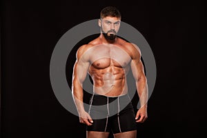 Strong Athletic Man Fitness Model Torso showing six pack abs. isolated on black background with copyspace