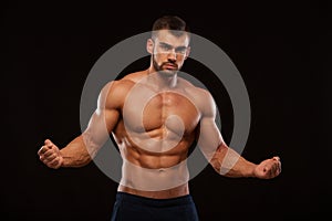 Strong Athletic Man Fitness Model Torso showing six pack abs. isolated on black background with copyspace