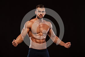 Strong Athletic Man Fitness Model Torso showing six pack abs. isolated on black background with copyspace