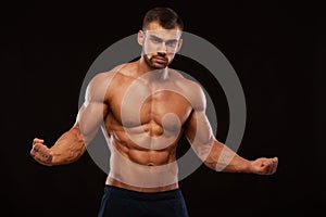 Strong Athletic Man Fitness Model Torso showing six pack abs. isolated on black background with copyspace