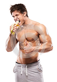 Strong Athletic Man showing muscular body and eating a banana