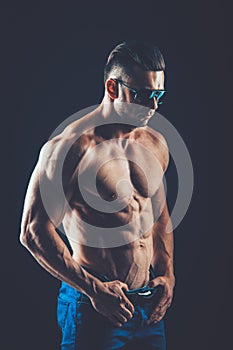 strong athletic man in sunglasses on black background