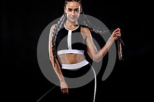 A strong athletic woman on black background wearing in black sportswear, fitness and sport motivation. Sport concept