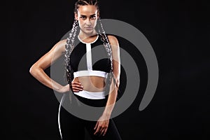 A strong athletic woman on black background wearing in black sportswear, fitness and sport motivation. Sport concept