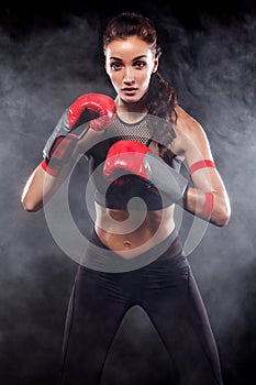 A strong athletic, woman boxer, boxing at training on the black background. Sport boxing Concept.