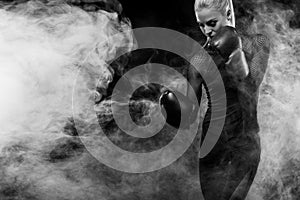 A strong athletic, woman boxer, boxing at training on the black background. Sport boxing Concept with copy space.