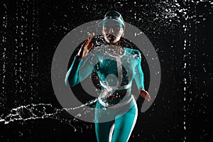 A strong athletic, woman sprinter, running on black background wearing in the mint color sportswea