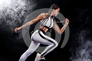 A strong athletic, woman sprinter, running on black background wearing in the sportswear, fitness and sport motivation